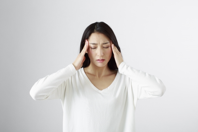 頭痛で側頭部を押さえる女性